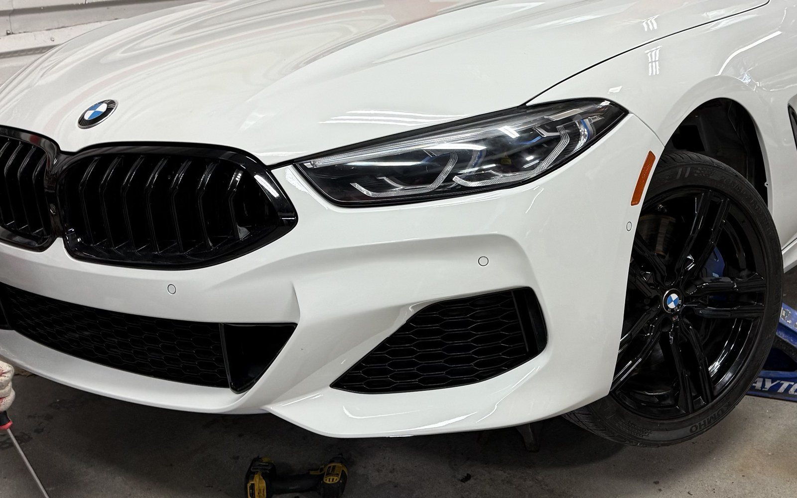 White BMW 8 Series front corner after auto body repair and PPG refinishing at Exclusive Collision & Repair in Brooklyn, NY, with the bumper, headlight and fender restored