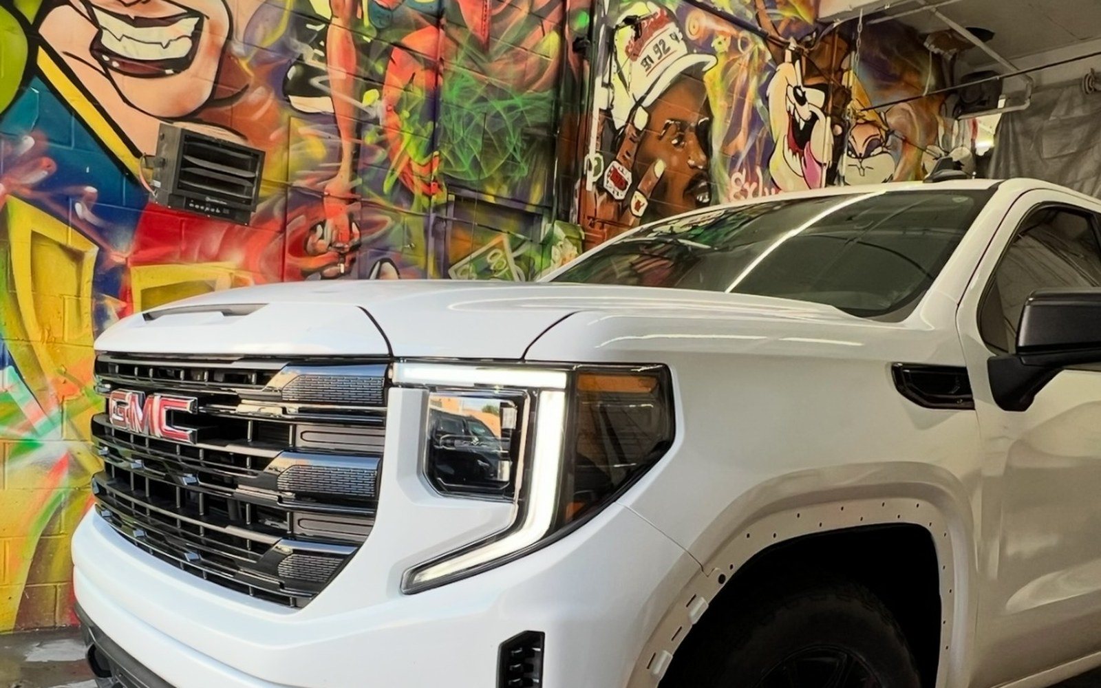 The same GMC Sierra after collision repair at Exclusive Collision & Repair in Brooklyn, NY, with a new grille, headlight and fender and a matched white finish