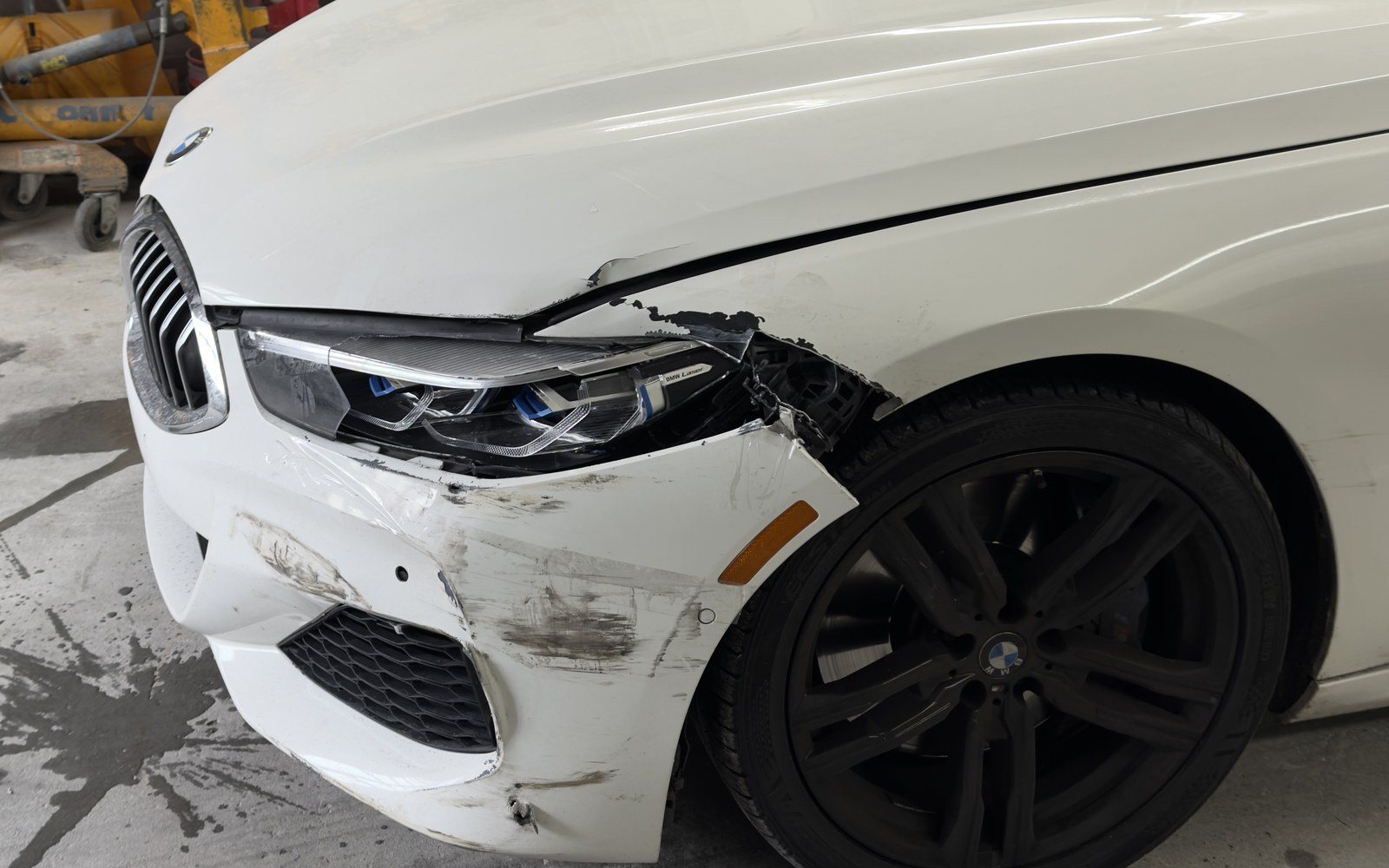 White BMW 8 Series with a torn front bumper, damaged headlight and scraped fender before collision repair at Exclusive Collision & Repair in Brooklyn, NY