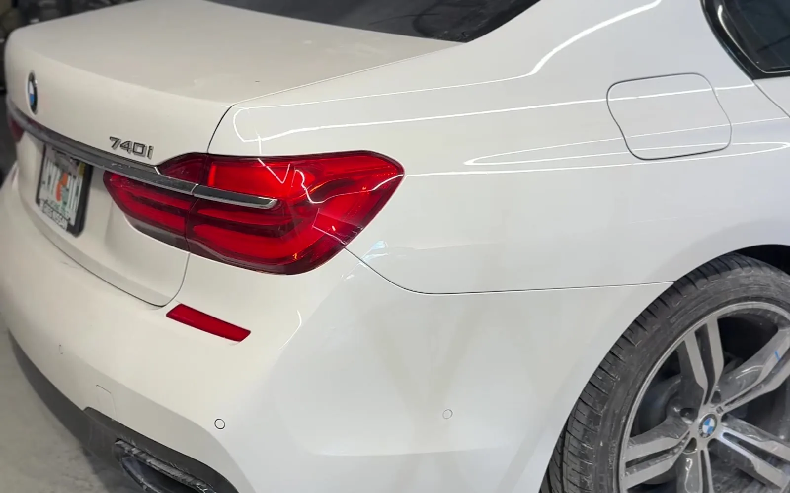 Same white BMW 740i rear quarter panel refinished to a color-matched gloss after car painting at Exclusive Collision & Repair in Brooklyn, NY