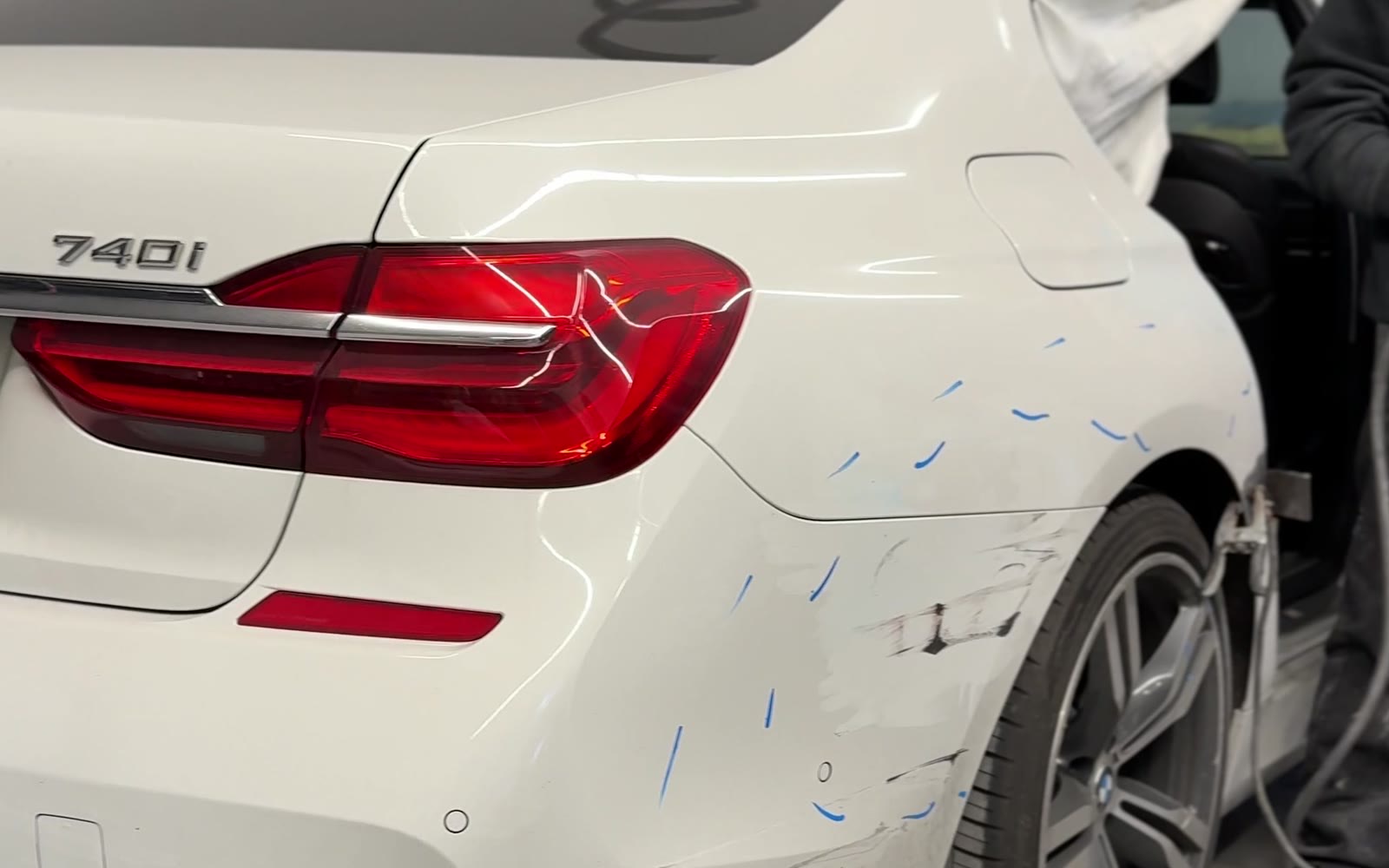 White BMW 740i rear quarter panel with scrapes and repair markup before car painting at Exclusive Collision & Repair in Brooklyn, NY