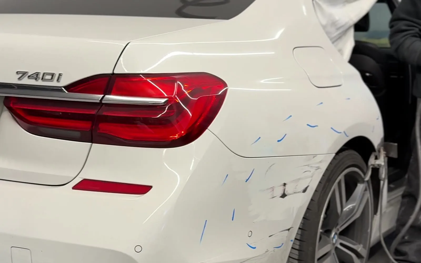 White BMW 740i rear quarter panel with scrapes and repair markup before car painting at Exclusive Collision & Repair in Brooklyn, NY