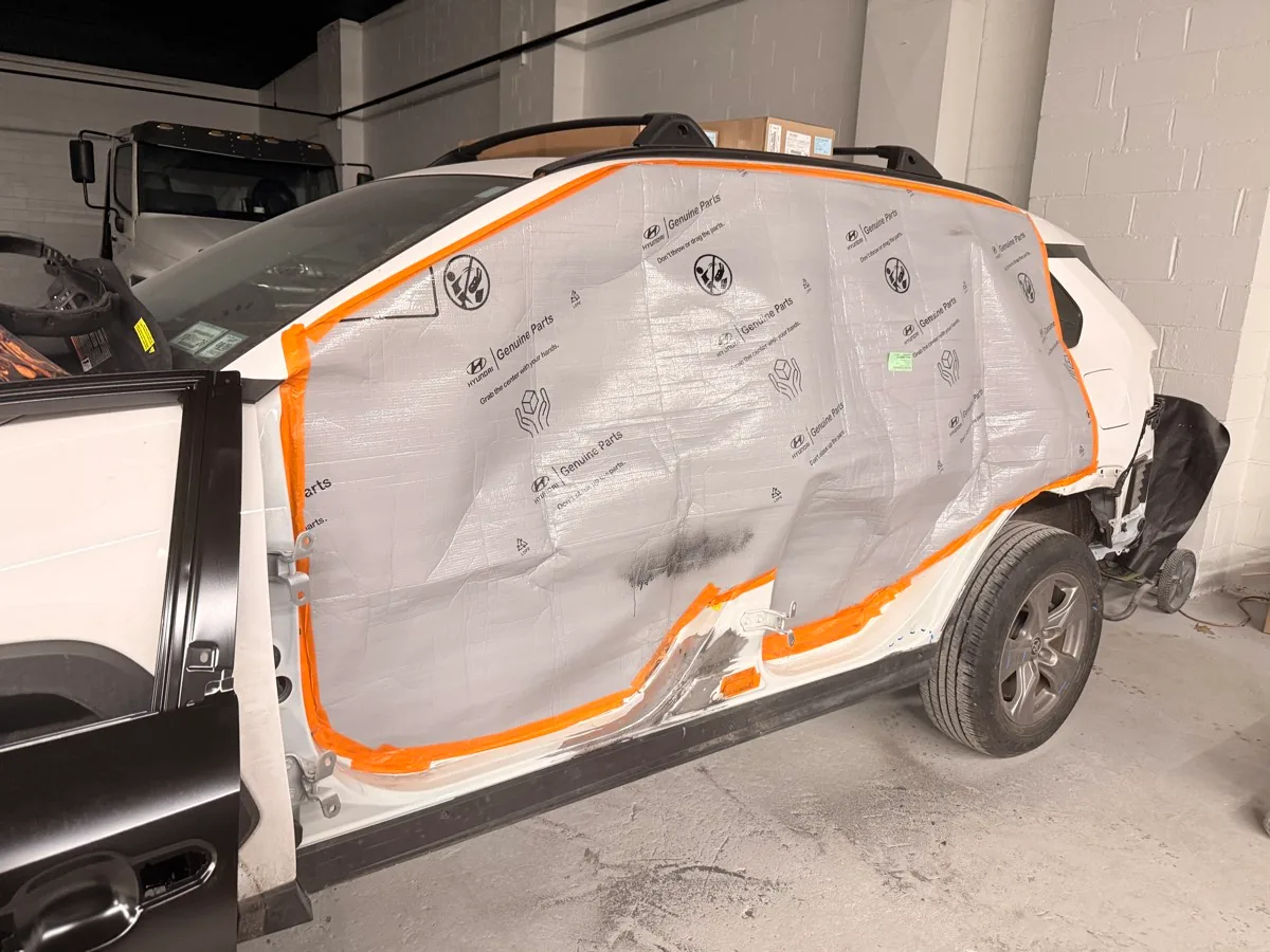 Car panel masked off with paper and tape, prepped for painting at Exclusive Collision & Repair in Brooklyn, NY
