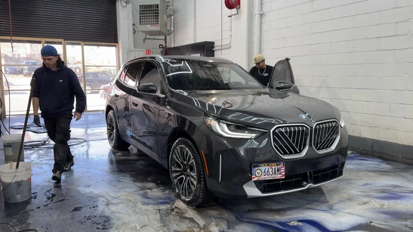 Exclusive Collision & Repair team detailing a BMW X3 in the wash bay of the Brooklyn, NY auto body shop