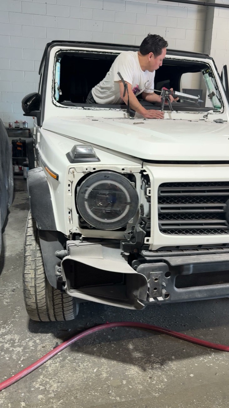 Technician applying sealant during front-end repair on a Mercedes G-Wagon at Exclusive Collision & Repair in Brooklyn, NY