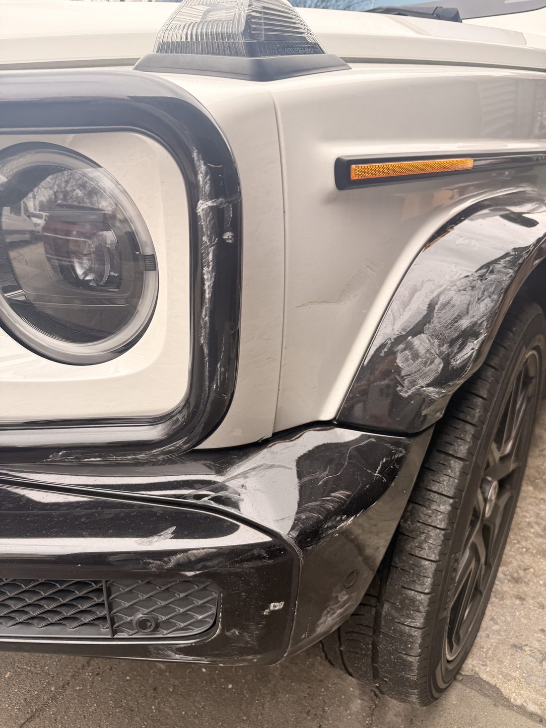 Close view of a scraped front fender and bumper corner on a Mercedes G Class before repair at Exclusive Collision & Repair in Brooklyn, NY