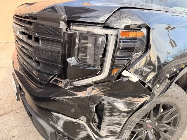 Front-end collision damage on a black GMC Sierra brought in to Exclusive Collision & Repair, an auto body shop in Brooklyn, NY that handles the insurance claim directly