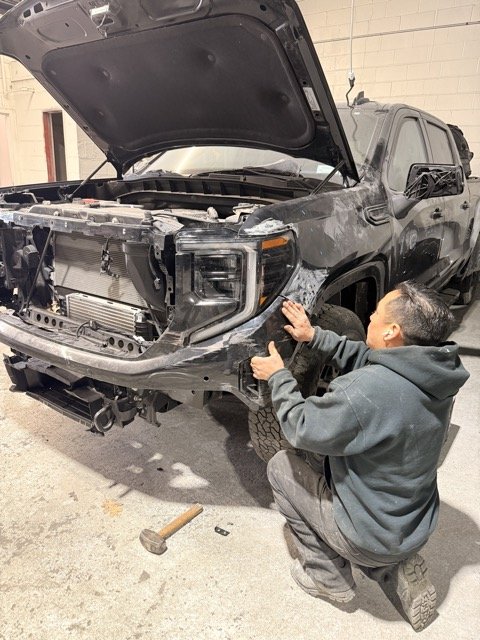Exclusive Collision & Repair technician test-fitting the front end of a GMC during collision repair at the auto body shop in Brooklyn, NY