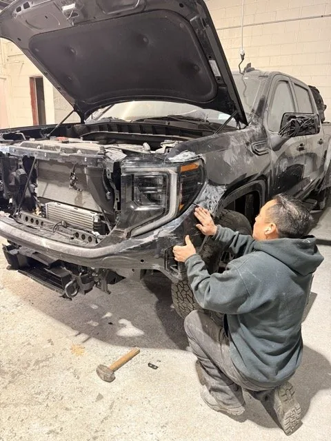Exclusive Collision & Repair technician fitting a front panel back to shape by hand in the Brooklyn, NY shop during a dent repair